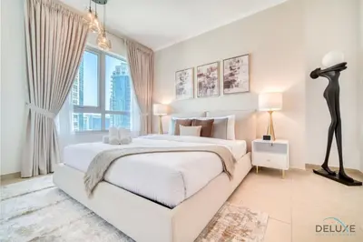 a white bedroom with a large bed and a large window at Glamorous 1BR at Residences 5 Downtown Dubai by Deluxe Holiday Homes in Dubai