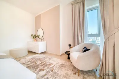 a white bedroom with a white chair and a window at Glamorous 1BR at Residences 5 Downtown Dubai by Deluxe Holiday Homes in Dubai