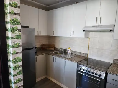 a kitchen with white cabinets and a stainless steel refrigerator at Upgraded 1 Bhk Silicon Oasis Short or long rental in Dubai