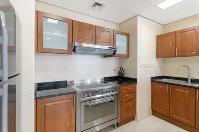 a kitchen with wooden cabinets and a stainless steel stove at Scenic lake view 2BR near metro in Cluster A, JLT - Allsopp&Allsopp in Dubai