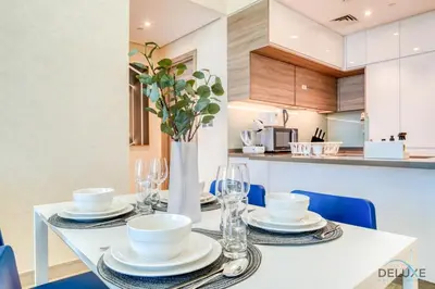 a dining table with plates and glasses and a vase at Peaceful 1BR in Studio One Dubai Marina by Deluxe Holiday Homes in Dubai