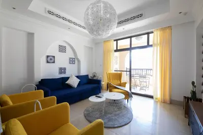 a living room with a blue couch and yellow chairs at Chic 2BR with Burj Khalifa View in Souk Al Bahar in Dubai