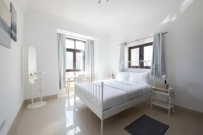 a white bedroom with a white bed and windows at Chic 2BR with Burj Khalifa View in Souk Al Bahar in Dubai