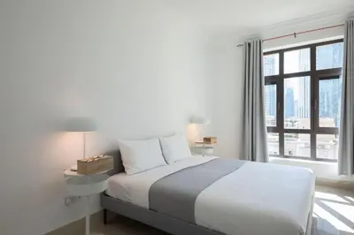 a white bedroom with a bed and a window at Chic 2BR with Burj Khalifa View in Souk Al Bahar in Dubai