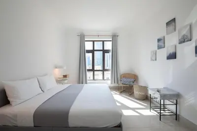a white bedroom with a large bed and a window at Chic 2BR with Burj Khalifa View in Souk Al Bahar in Dubai