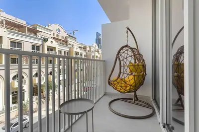a balcony with a rattan basket and a chair at Silkhaus cozy studio in JVC Luma21 in Dubai