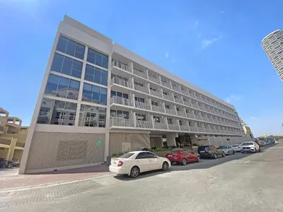 a large building with cars parked in a parking lot at Silkhaus cozy studio in JVC Luma21 in Dubai