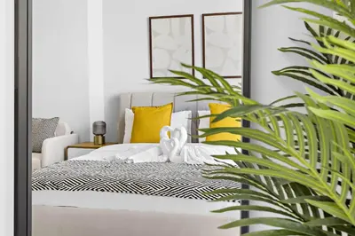 a bedroom with a bed with yellow pillows and a mirror at Silkhaus cozy studio in JVC Luma21 in Dubai