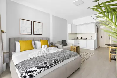 a bedroom with a large bed and a living room at Silkhaus cozy studio in JVC Luma21 in Dubai