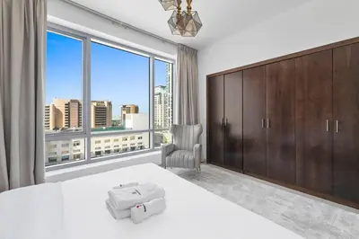 a bedroom with a white bed and a large window at StoneTree - Park Island Blakely 1 BR - Prime location in Dubai