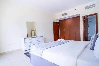 a white bedroom with a bed and a dresser at RH- City Center Retreat,1BR, walk to Burj Khalifa in Dubai