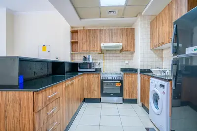 a kitchen with wooden cabinets and a washer and dryer at RH- City Center Retreat,1BR, walk to Burj Khalifa in Dubai