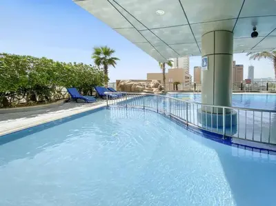 a large swimming pool with blue chairs in a building at StoneTree - Ocean Heights 1 BR - High Floor in Dubai