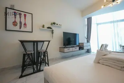 a bedroom with a bed and a table and a television at Mira Holiday Homes - Fully furnished Studio in Business Bay in Dubai