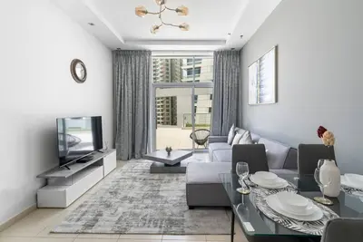 a living room with a couch and a tv at StoneTree - SkyView Tower 1 BR - Best Location in Dubai
