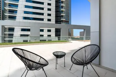 two chairs sitting on a balcony with a view of a building at StoneTree - SkyView Tower 1 BR - Best Location in Dubai
