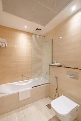 a bathroom with a tub and a toilet and a sink at Peony Hotel in Dubai