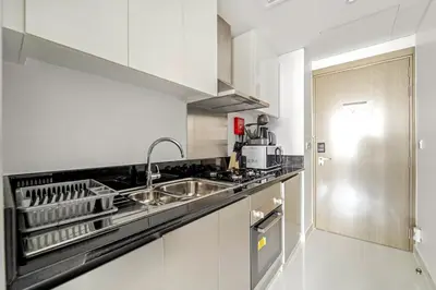a white kitchen with a sink and a stove at ALiving Elegant Studio with Balcony I Canal View I DAMAC Maison Prive- 706B in Dubai