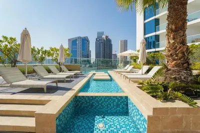 a swimming pool with chaise lounge chairs and a hotel at ALiving Elegant Studio with Balcony I Canal View I DAMAC Maison Prive- 706B in Dubai