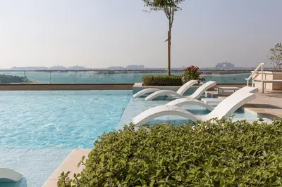 a swimming pool with two white chairs in the water at Sea View with Private Beach Access! 3BR & Maid Rm in Dubai