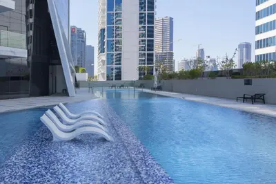 a swimming pool with two white seats in a city at Marquise Square - 2Br Apartment - Allsopp&Allsopp in Dubai