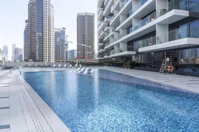 a swimming pool in front of a building with tall buildings at Marquise Square - 2Br Apartment - Allsopp&Allsopp in Dubai