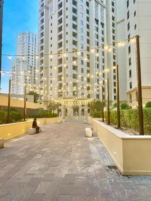 a person sitting on a bench in front of a large building at JBR Beach - Panoramic Sea View 2BR Apartment in Dubai