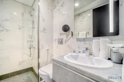 a white bathroom with a sink and a shower at Classic 1BR at MAG 510 Dubai South by Deluxe Holiday Homes in Dubai