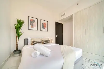 a white bedroom with a large white bed with pillows at Classic 1BR at MAG 510 Dubai South by Deluxe Holiday Homes in Dubai