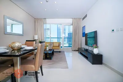 a living room with a dining table and a television at Alashrafia Saray - Spectacular 2BR in Canal Views in Dubai