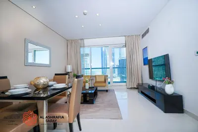 a living room with a dining table and a television at Alashrafia Saray - Spectacular 2BR in Canal Views in Dubai
