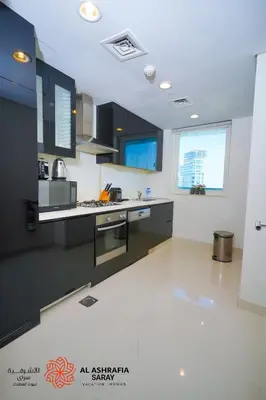a kitchen with black cabinets and a white floor at Alashrafia Saray - Spectacular 2BR in Canal Views in Dubai