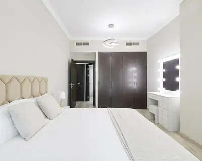 a white bedroom with a large bed and a television at 1 bedroom in Torch Tower Dubai Marina in Dubai
