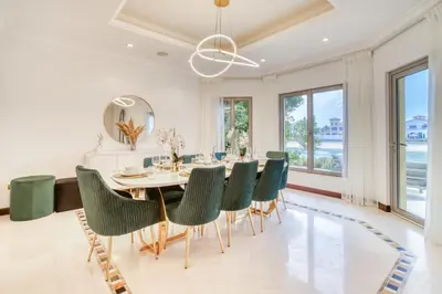 a dining room with a table and green chairs at Frond E Villa, Palm Jumeirah - Mint Stay in Dubai