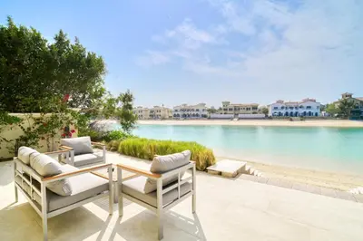a patio with a table and chairs next to a body of water at Frond E Villa, Palm Jumeirah - Mint Stay in Dubai