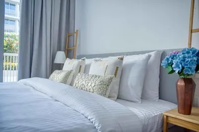 a bed with white pillows and a vase with blue flowers at The Smart Concierge - Luma 21 in Dubai