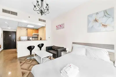 a bedroom with a white bed and a kitchen at StoneTree - Marina Diamond Studio - Near Metro Station in Dubai