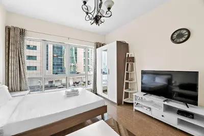a living room with a large bed and a flat screen tv at StoneTree - Marina Diamond Studio - Near Metro Station in Dubai