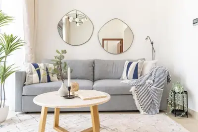 a living room with a couch and a table and a mirror at Vogue Marina Gate near JBR Beach and Marina Mall, One Bedroom Apartment with Balcony and city skyline view, Access to all Amenities in Dubai