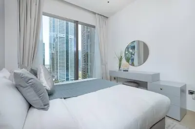 a white bedroom with a large bed and a mirror at Vogue Marina Gate near JBR Beach and Marina Mall, One Bedroom Apartment with Balcony and city skyline view, Access to all Amenities in Dubai