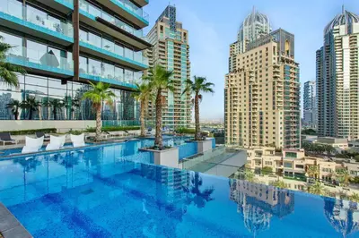 a pool on the roof of a building with palm trees at Vogue Marina Gate near JBR Beach and Marina Mall, One Bedroom Apartment with Balcony and city skyline view, Access to all Amenities in Dubai