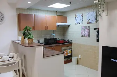 a kitchen with wooden cabinets and a counter top at Newly furnished cozy 1 bedroom apartment close to JBR beach and metro in Dubai