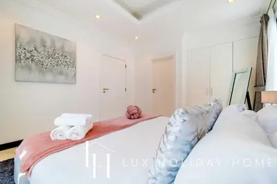 a white bedroom with two beds and towels at LUX The Ultimate Island Palm Villa in Dubai
