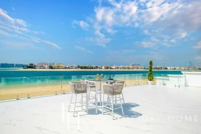 a table and chairs on a patio next to the water at LUX The Ultimate Island Palm Villa in Dubai