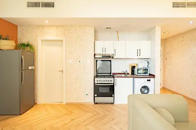 a kitchen with white appliances and a living room at Scala Tower Central Chic with a twist studio in Dubai