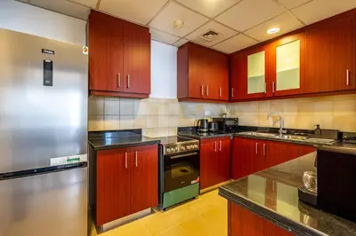 a kitchen with wooden cabinets and a stainless steel refrigerator at Spacious 2BR - Dubai Eye & Sea View - JBR in Dubai