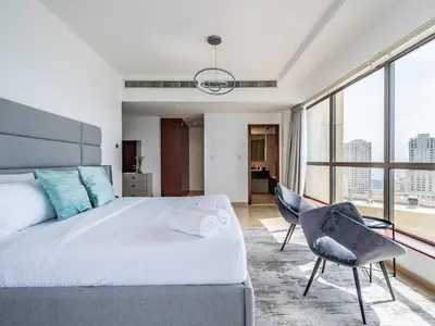 a bedroom with a large bed and a chair at Spacious 2BR - Dubai Eye & Sea View - JBR in Dubai