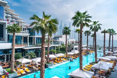 an image of a resort pool with palm trees at Maison Privee - Glamourous Apt with Sea Views at FIVE Palm in Dubai