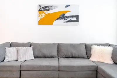 a grey couch in a living room with a painting on the wall at Stunning 2BR Apartment in Port De La Mer in Dubai