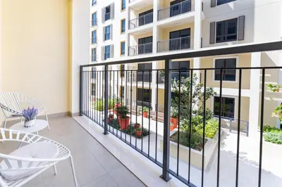 a balcony with chairs and tables and a building at Stunning 2BR Apartment in Port De La Mer in Dubai